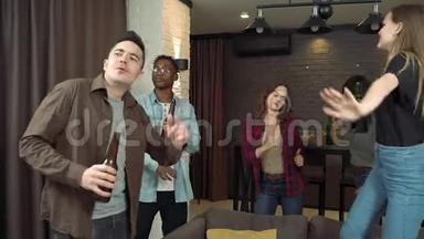 多种族的年轻人正在跳舞喝啤酒，在客厅的家庭聚会上玩得很开心。 <strong>青年</strong>和假<strong>日</strong>概念